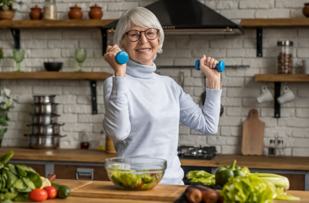 A senior woman holding small weights preparing a healthy salad as part of her keto diet.