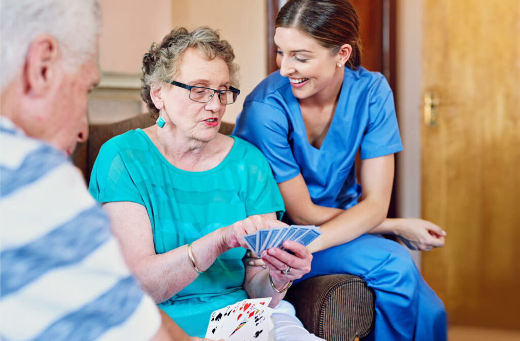 A caregiver laughing while a resident in assisted living explains how to play a card game.