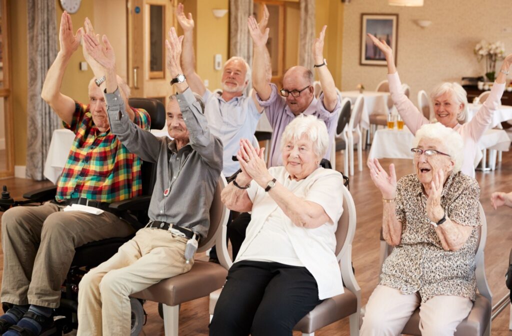 A group of seniors happily raising their arms in the air and clapping to a song being played.